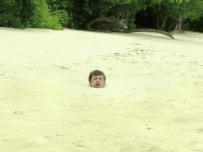 A Man Is Buried In The Sand On The Beach GIF