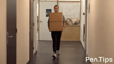 A Man Is Carrying A Cardboard Box Down A Hallway With Pen Tips Written On The Bottom Of The Image GIF