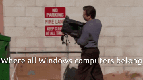 A Man Is Carrying A Computer In Front Of A Sign That Says No Parking Fire Lane GIF