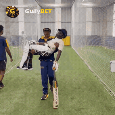 A Man Is Carrying A Cricket Player In His Arms With Gullybet Written On The Bottom GIF