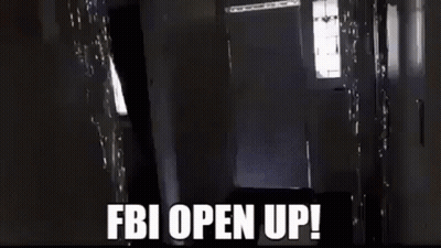 A Man Is Carrying A Large Box In A Hallway And The Words `` Fbi Open Up '' Are Written On The Screen . GIF