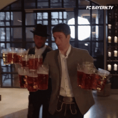 A Man Is Carrying A Stack Of Beer Mugs With The Fc Bayern.tv Logo In The Corner GIF