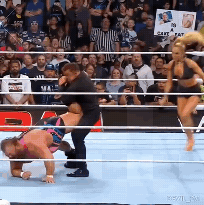 A Man Is Carrying A Woman In A Wrestling Ring With A Sign That Says Is A Cake Eat . GIF