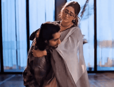 A Man Is Carrying A Woman In His Arms In A Room . GIF