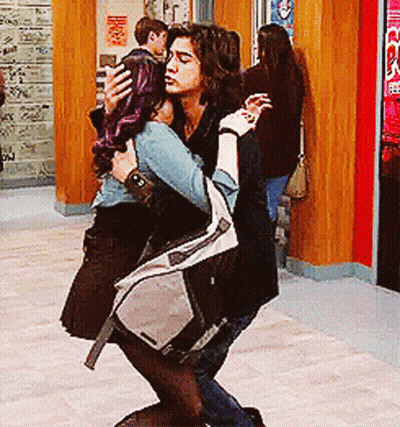 A Man Is Carrying A Woman In His Arms In Front Of A Sign That Says Co GIF