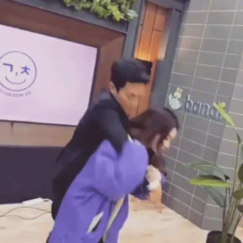 A Man Is Carrying A Woman On His Back In Front Of A Building . GIF