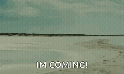 A Man Is Carrying A Woman On His Shoulders On A Beach And Saying `` Im Coming '' . GIF