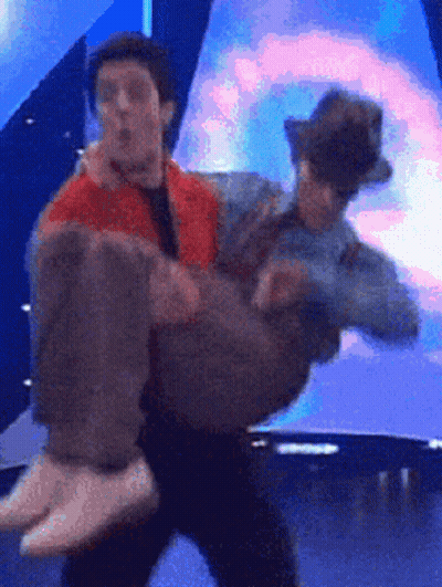 A Man Is Carrying Another Man In His Arms GIF