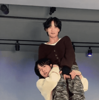A Man Is Carrying Another Man On His Back On A Stage . GIF