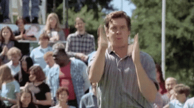 A Man Is Clapping His Hands In Front Of A Crowd . GIF