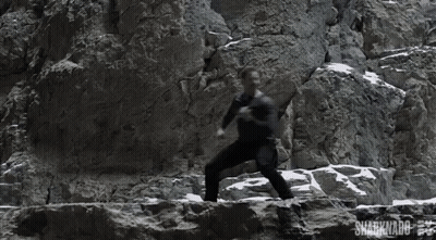A Man Is Climbing A Rock Wall With The Words Sharknado On The Bottom Right GIF