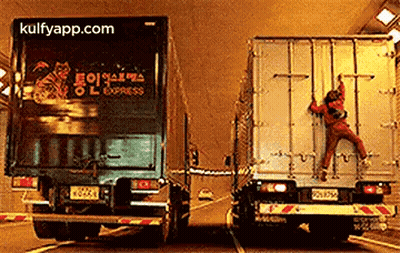 A Man Is Climbing On The Back Of A Semi Truck . GIF