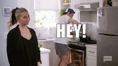 A Man Is Cooking In A Kitchen And A Woman Is Standing In Front Of Him With The Words Hey Written Above Him GIF