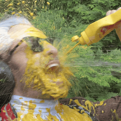 A Man Is Covered In Mustard While Holding A Bottle GIF