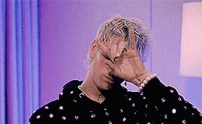 A Man Is Covering His Face With His Hand And Making A Peace Sign . GIF