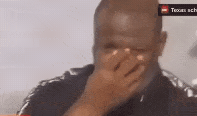 a man is covering his face with his hand in front of a sign that says texas