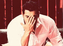 A Man Is Covering His Face With His Hand GIF