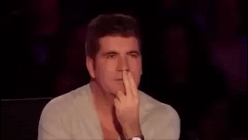 A Man Is Covering His Face With His Hand While Sitting In A Chair . GIF