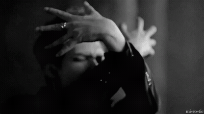 A Man Is Covering His Face With His Hands In A Black And White Photo . GIF
