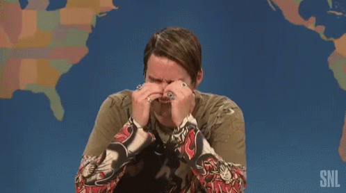 A Man Is Covering His Face With His Hands While Sitting In Front Of A Map Of The United States . GIF