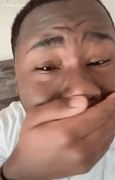 A Man Is Covering His Mouth With His Hand While Laughing . GIF