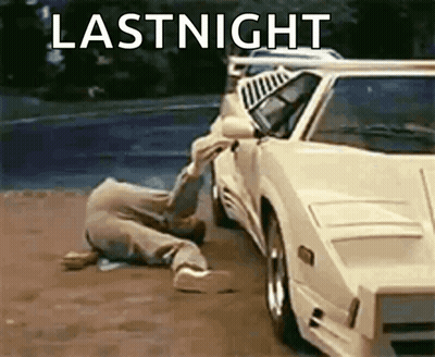 A Man Is Crawling On The Ground Next To A White Car With The Words Lastnight Written On It . GIF