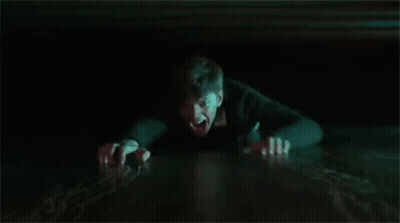 A Man Is Crawling Out Of A Hole In The Floor In The Dark . GIF