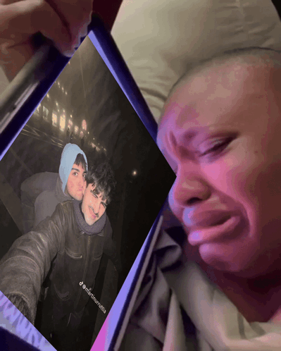 A Man Is Crying While Looking At A Picture Of Himself And Another Man On A Phone GIF