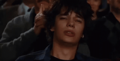 A Man Is Crying While Sitting In A Crowd Of People Watching A Movie . GIF