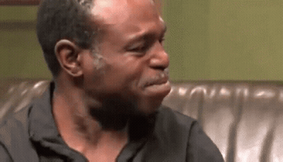 A Man Is Crying While Sitting On A Couch And Making A Funny Face . GIF