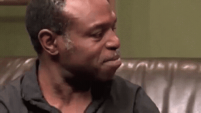 A Man Is Crying While Sitting On A Couch In A Room . GIF