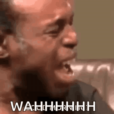 A Man Is Crying While Sitting On A Couch With His Mouth Open And The Words Wahh Written On His Face . GIF