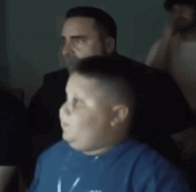A Man Is Cutting A Boy 'S Hair In A Barber Shop . GIF