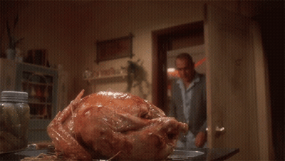 A Man Is Cutting A Large Turkey On A Table GIF