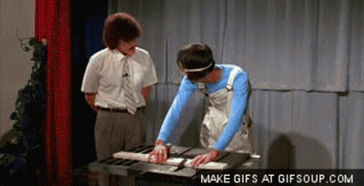 A Man Is Cutting A Piece Of Wood On A Table Saw While Another Man Looks On GIF