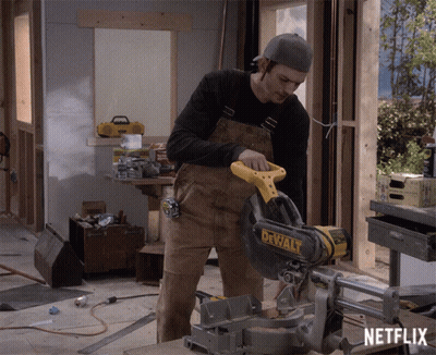 A Man Is Cutting A Piece Of Wood With A Dewalt Circular Saw GIF