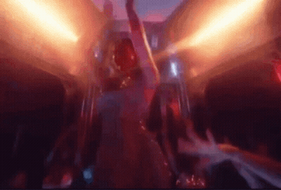 A Man Is Dancing In A Club With His Arms In The Air And A Crowd Behind Him . GIF