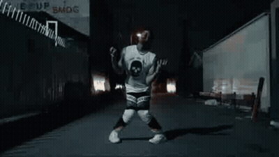 A Man Is Dancing In A Dark Alleyway At Night . GIF