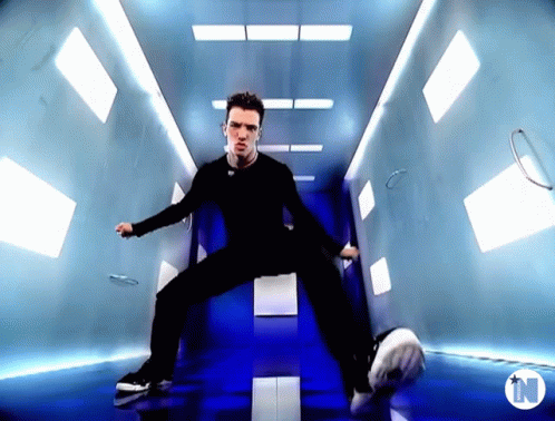 A Man Is Dancing In A Hallway With A N On The Bottom GIF