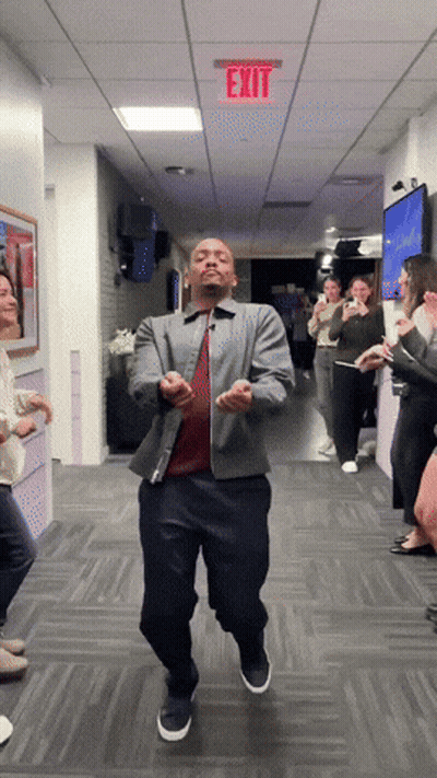 A Man Is Dancing In A Hallway With A Red Exit Sign Above Him GIF