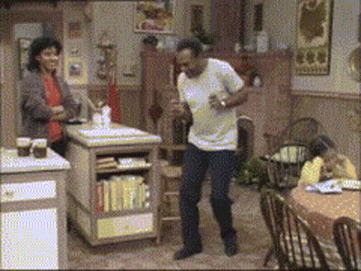 A Man Is Dancing In A Kitchen While A Woman Looks On GIF