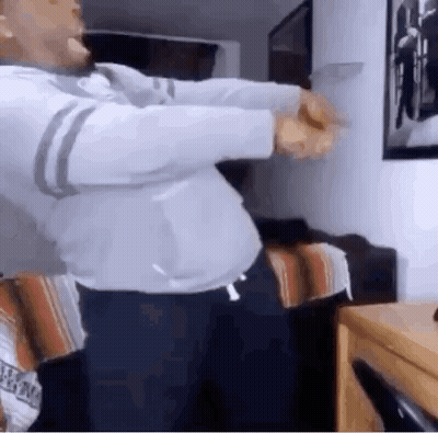 A Man Is Dancing In A Living Room In Front Of A Wall . GIF