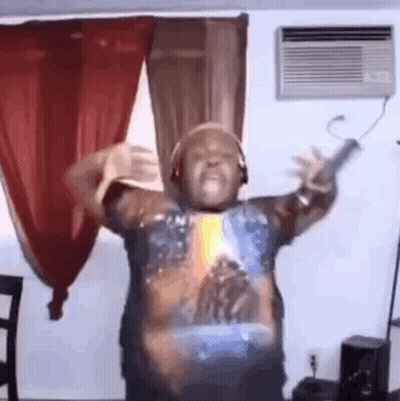 A Man Is Dancing In A Living Room Wearing Headphones And A Star Wars Shirt . GIF
