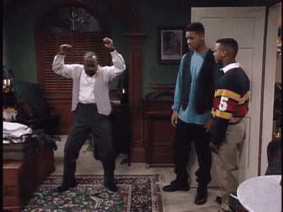 A Man Is Dancing In A Living Room While Two Other Men Stand Behind Him . GIF