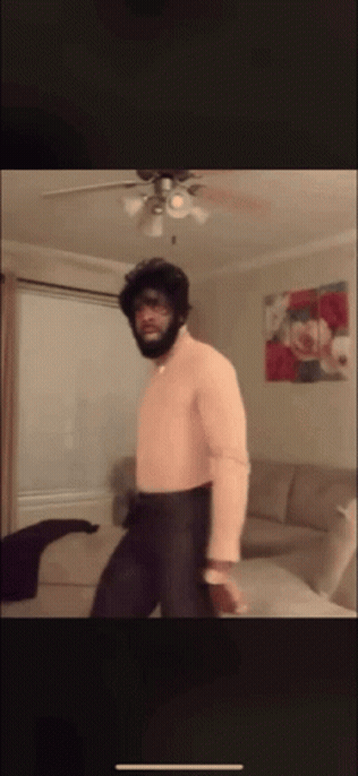 A Man Is Dancing In A Living Room With A Ceiling Fan GIF