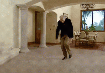 A Man Is Dancing In A Living Room With Columns And A Dining Table . GIF
