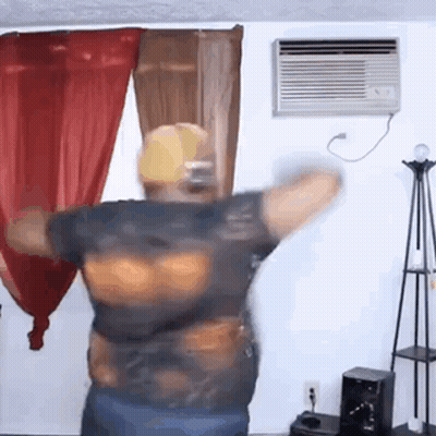 A Man Is Dancing In A Living Room With Red Curtains . GIF