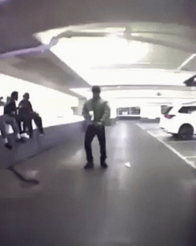 A Man Is Dancing In A Parking Garage With A Group Of People . GIF