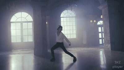 A Man Is Dancing In A Room With A Skz Player Logo GIF