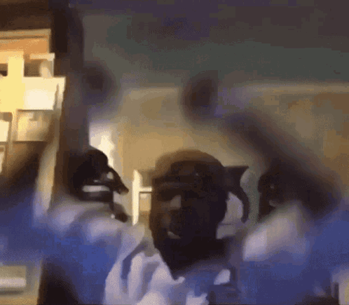 A Man Is Dancing In A Room With His Arms In The Air GIF